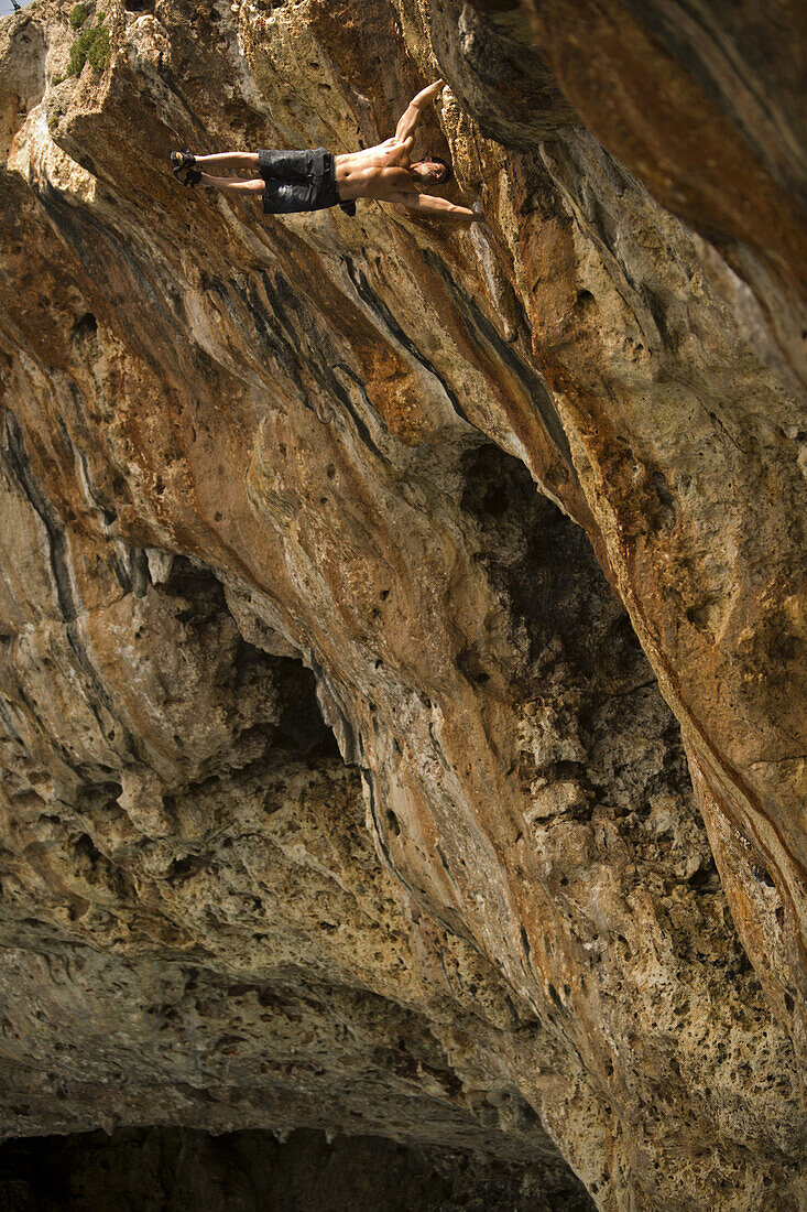 Miguel Riera does a handstand while deep water soloing / rock climbing in Mallorca, Spain.