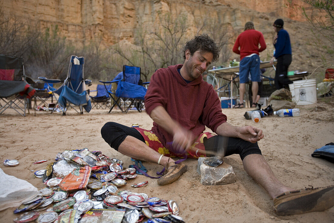 Jim Crossland smashing cans to make them smaller and easier to pack out during 18 day raft trip, Grand Canyon, Arizona, USA.