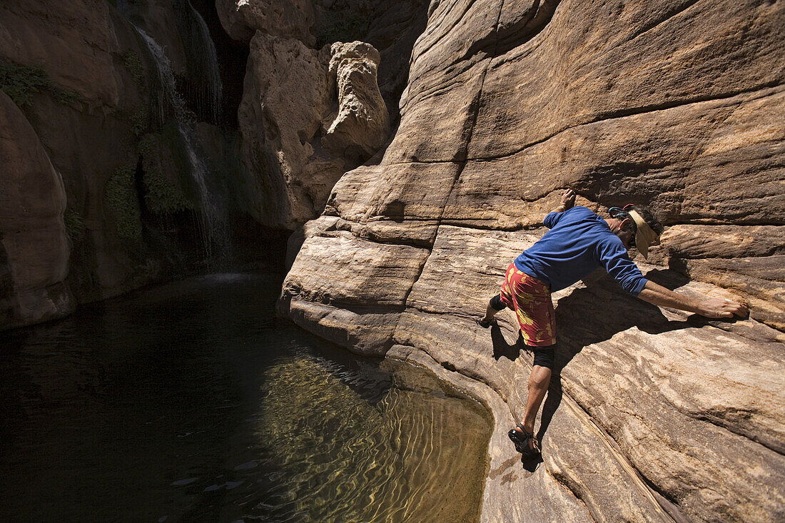Jim Crossland traversing on rock above pool in Elves Chasm, Grand Canyon, Arizona, USA.