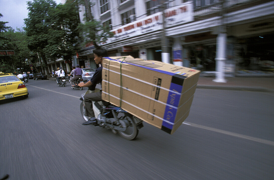 A man carrying a refrigerator on his motorcycle in Hanoi, Vietnam.