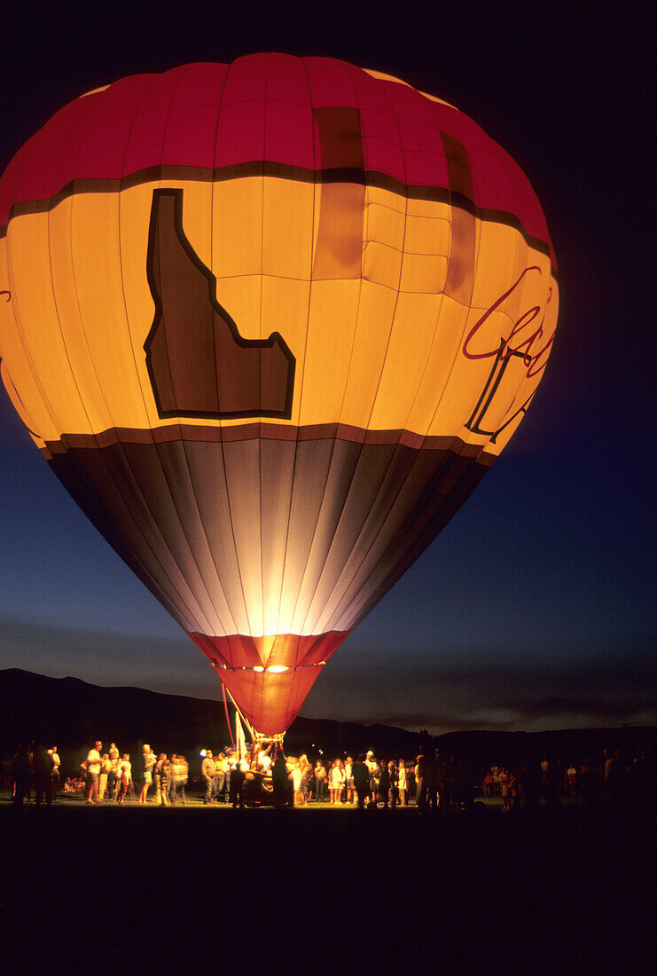 A crowd of people surround a hot air balloon at night during the Balloon Festival in Salmon, Idaho.