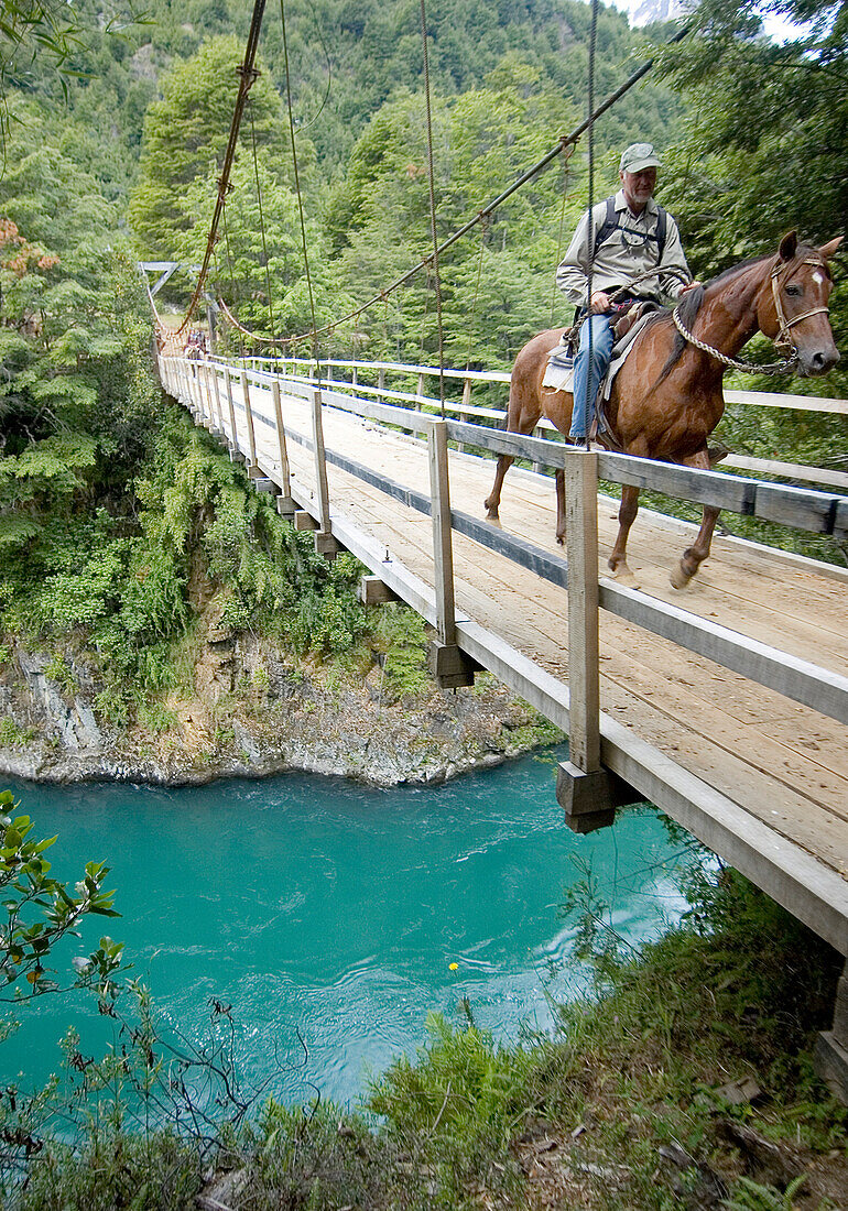 Kelly Reber rides a horse across a bridge in Futaleufu, Chile.