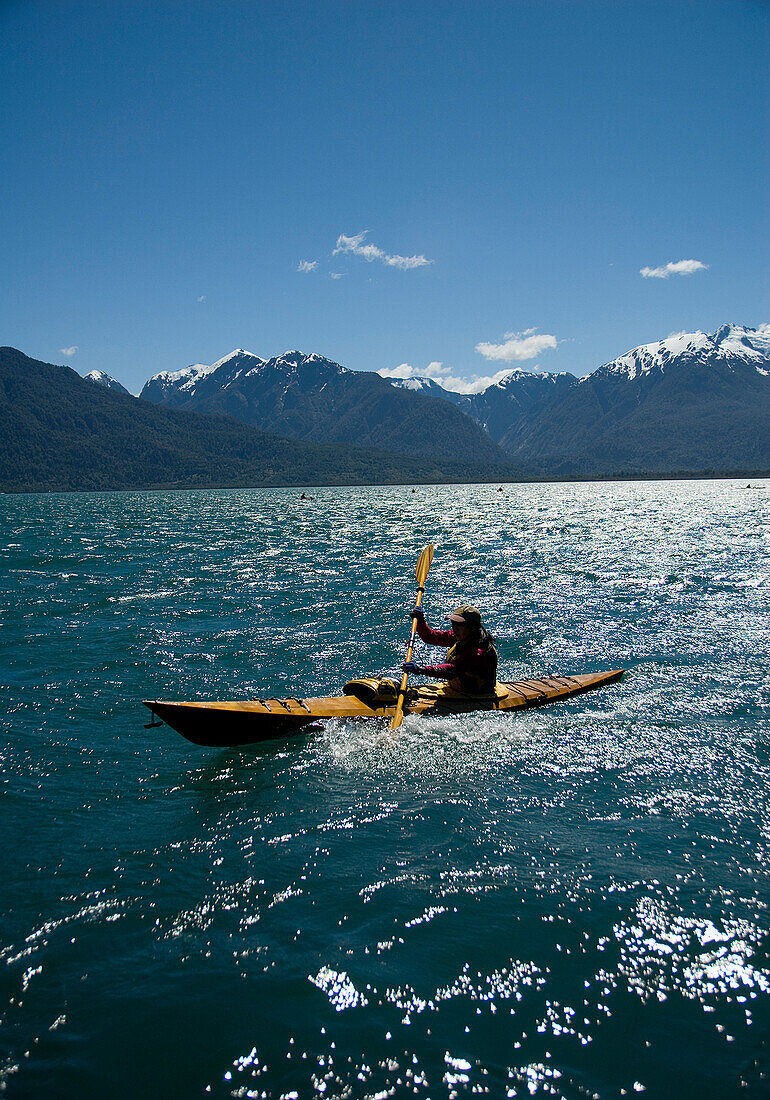 A person paddles a sea kayak during a wilderness adventure in Lago Yelcho, Chile.