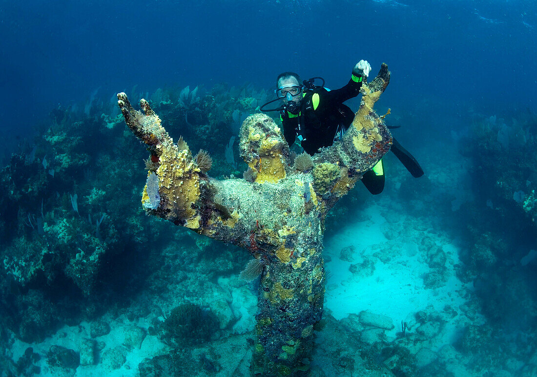Scuba diver, Daniel Brown pauses next to the Statue of Christ of the Abyss, located on a coral reef in the Florida Keys National Marine Sanctuary, Key Largo, Florida.
