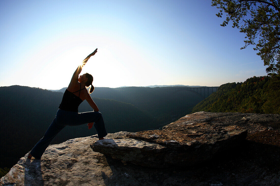 Sarah Chouinard enjoys a late afternoon yoga session pose : Side Angle - parsvakonasana, atop the Bosnian Buttress along the rim of the New River Gorge near Fayetteville, WV