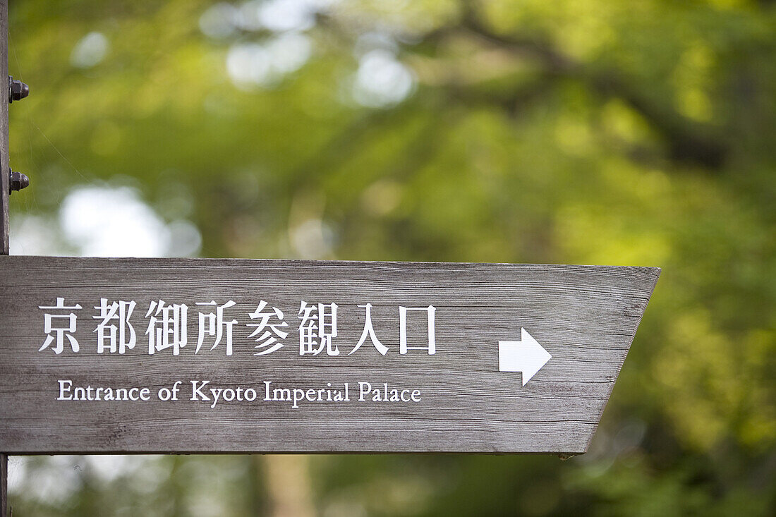 Sign for former Imperial Palace grounds now a park, written in Japanese and English with trees in background in Kyoto, Japan.