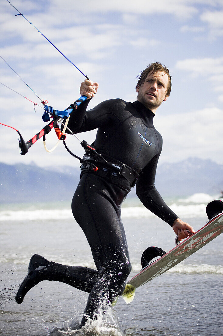 Traveler Terpening carries his kiteboard as he heads out for a kitesurfing session in Homer, Alaska on July 21, 2007.