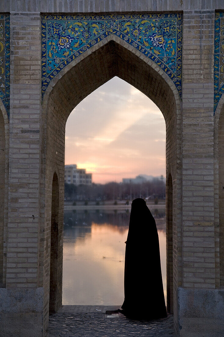 Esfahan, Iran - February, 2008: Iranian woman in one of the many arches on Khaju Bridge in Esfahan, Iran which spans the Zayandeh River and is a popular hangout for locals in the evening.