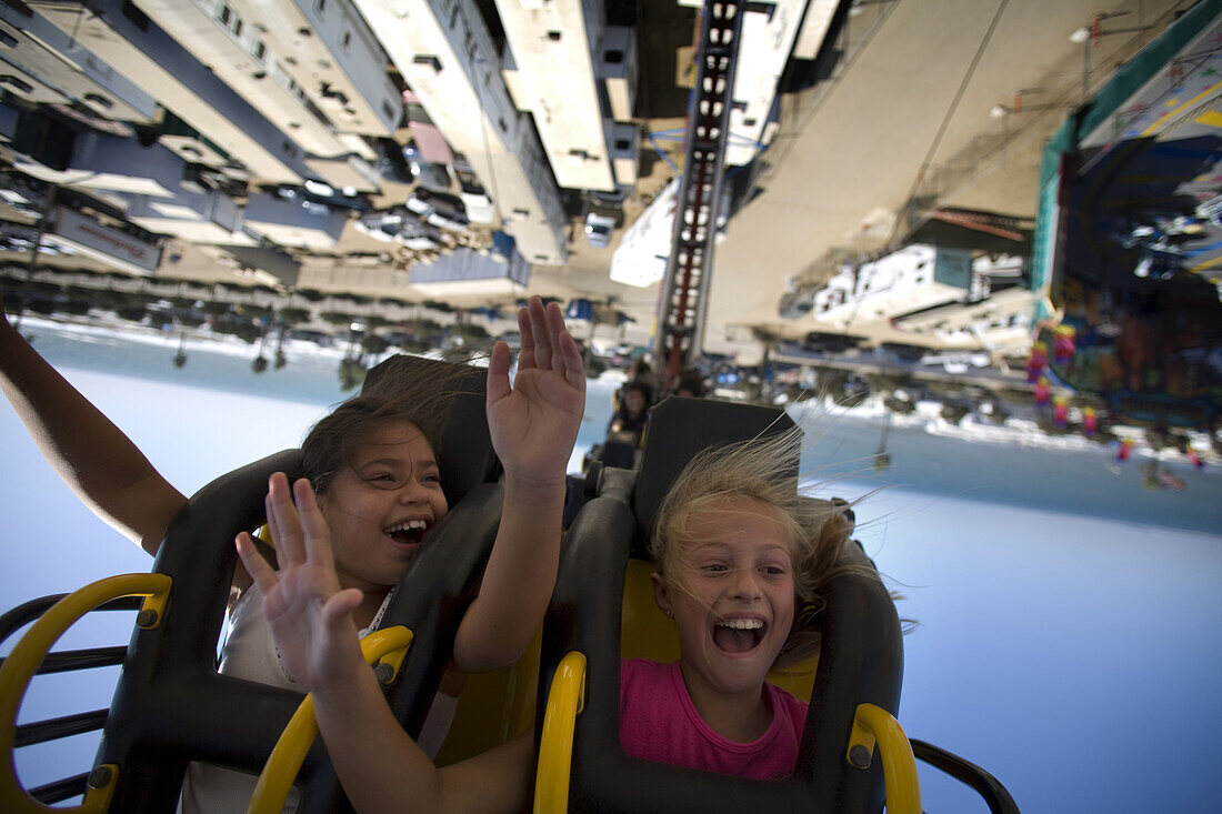 Two young girls sceam upside down on a carnival ride at the Ventura County Fair in California.