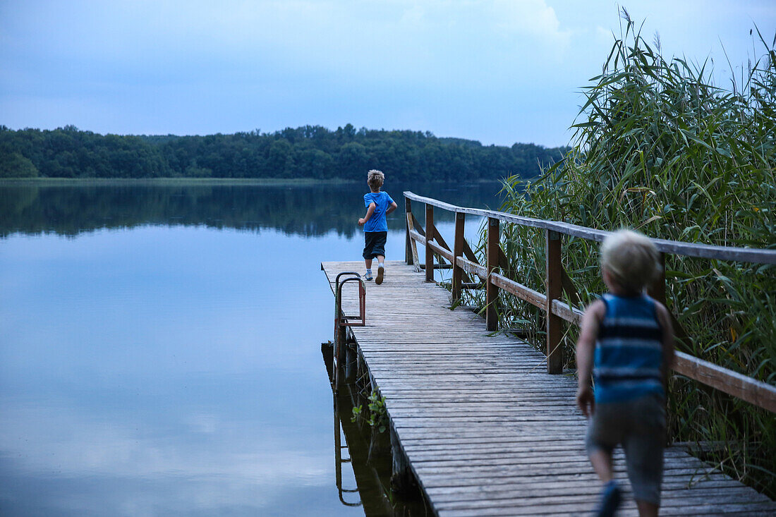 Zwei Jungen laufen über einen Steg an einem See, Biosphärenreservat Schorfheide-Chorin, Neudorf, Friedenfelde, Uckermark, Brandenburg, Deutschland
