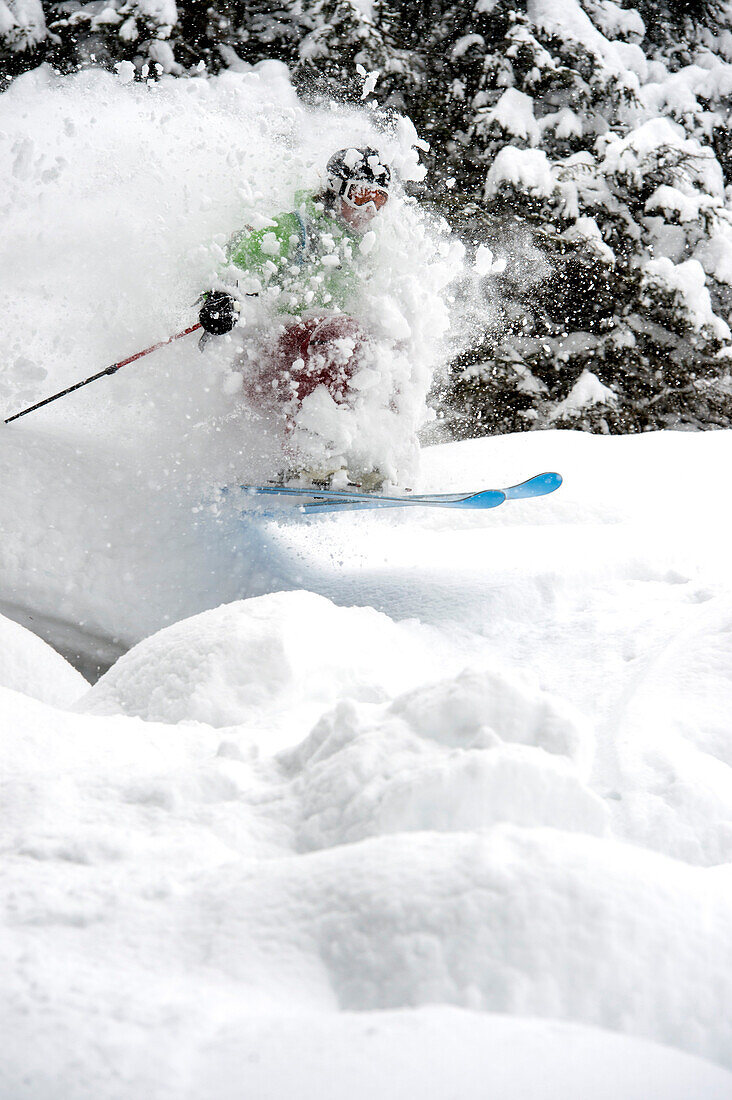 Skifahrer im Wald fährt Lichtung hinab und springt aus einer Schneewolke heraus, Gerlos, Zillertal, Österreich