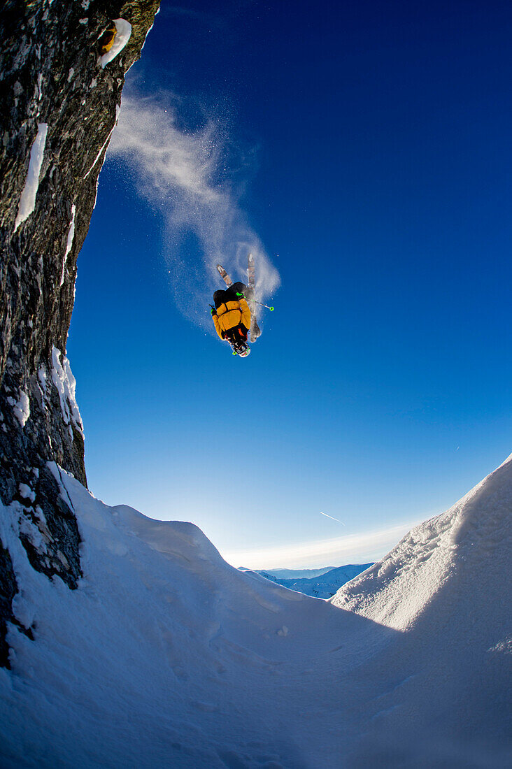 Skier doing a back flip over rocks, head down, Hochfuegen, Zillertal, Austria