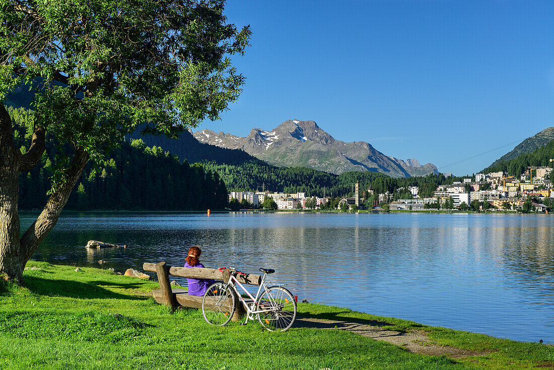 Radfahrerin rastet auf einer Bank am St. Moritzersee, St. Moritz, Oberengadin, Engadin, Kanton Graubünden, Schweiz
