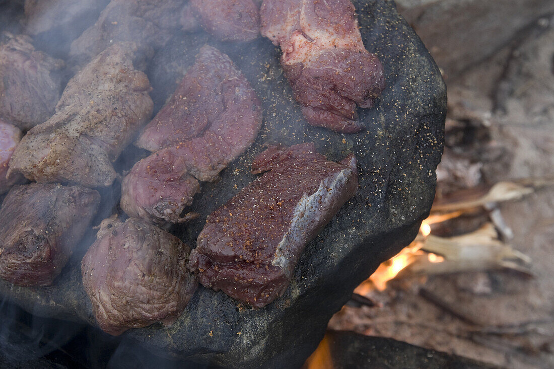 Traditional Greenlandic barbeque on a stone of caribou and whale meat at the Norse site of Sandnaes Sandy Point, Greenland.