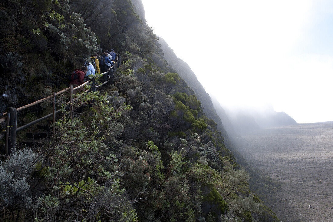 Hikers on the steep caldera wall on the Piton de la Fournaise, Reunion Island's active volcano. On August 1, 2010 the spectacular pitons, cirques and remparts of Reunion Island were inscribed in UNESCO's list of world heritage sites.
