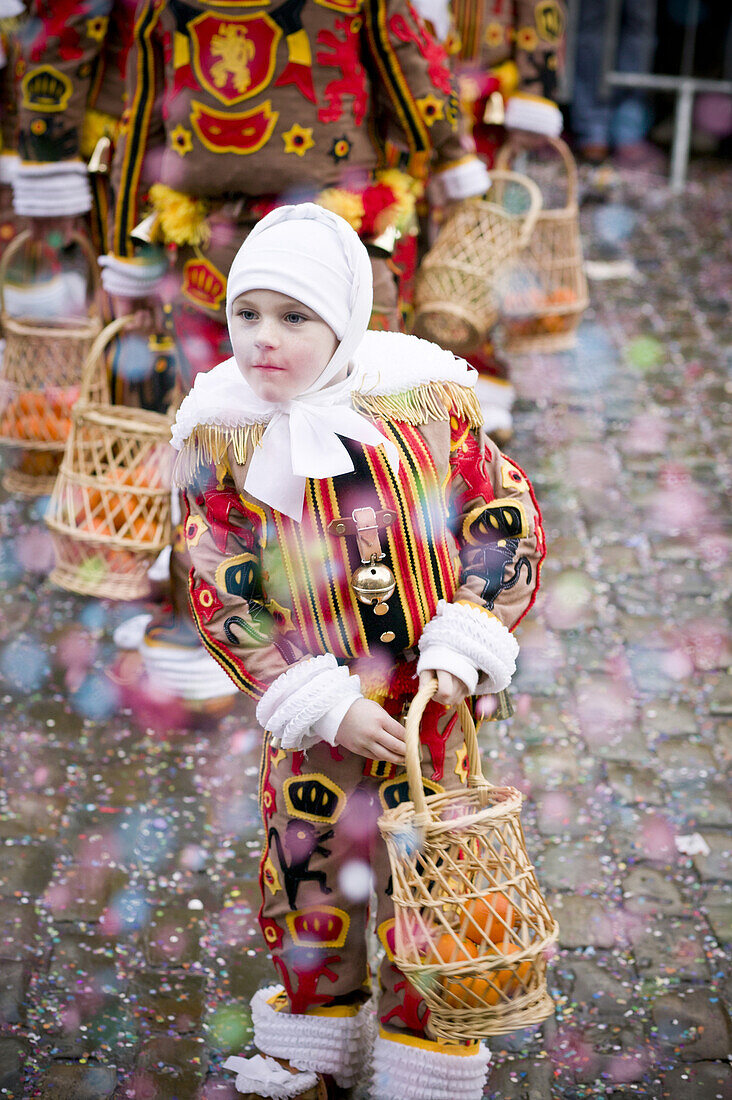 A young Gille reaches into his basket for an orange to throw to the crowd during the Carnival of Binche, Belgium. The Carnival is one of the oldest in the Wallonia area, dating back to approximately the 14th Century. It is famous for its' Gille, a charact