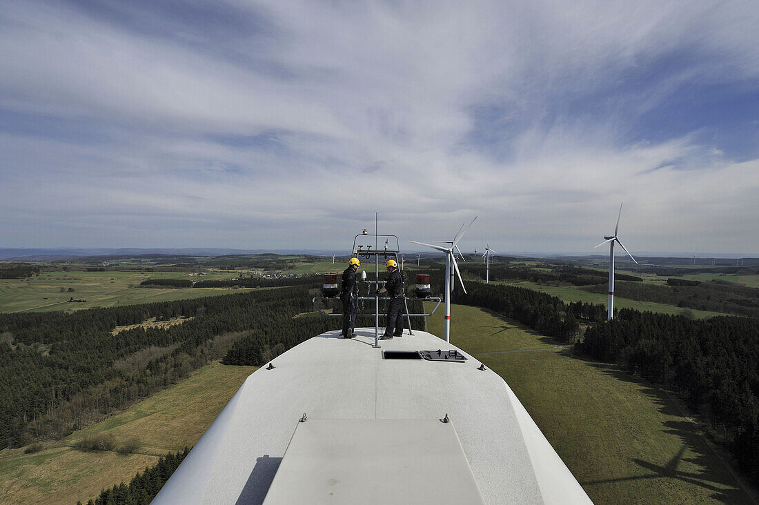 Two technician discuss on top of the nacelle of a wind turbine in Germany.