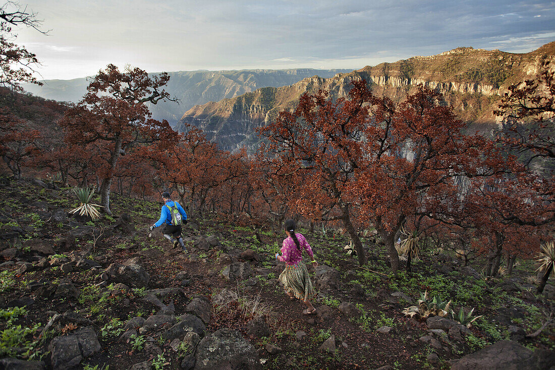 A runner is closely followed by a Tarahumara woman running down a canyon at the Ultramaraton de los Canones in Chihuahua, Mexico.