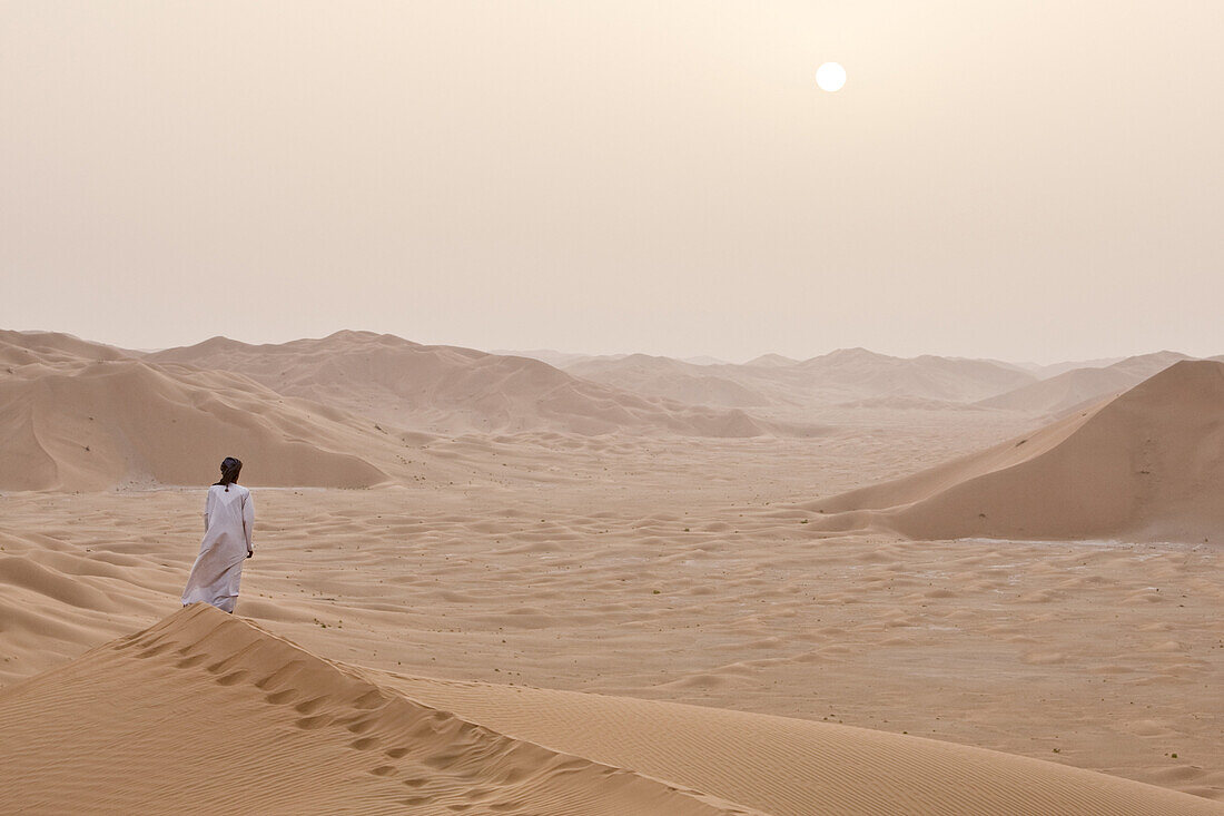 A man alone on the sand dunes of the Empty Quarter, Ar Rub Al Khali, Oman.