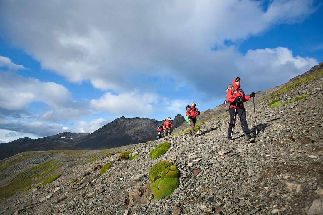 A group of  people wearing red jackets trekking in Tierra del Fuego,  Patagonia,  Chile.