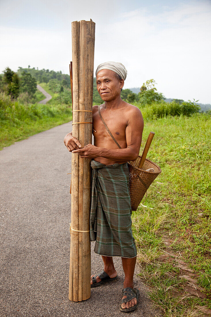 Bandarban,  Bangladesh - July 2011: Portrait of man carrying bamboo on a road outside Bandarban,  in the Chittagong hill tracts near the Burma border.