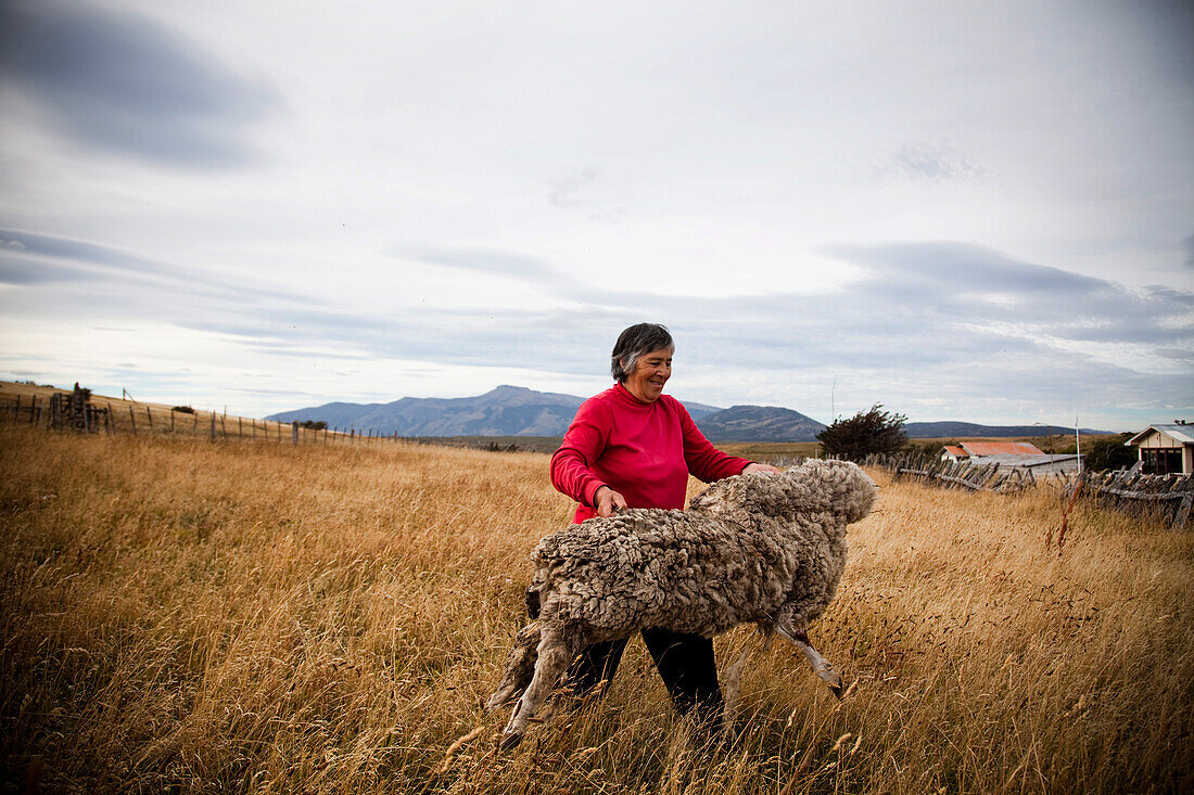 PATAGONIA, CHILE. A portrait of a woman holding the skin of a sheep. She farms her land as her family has for decades.