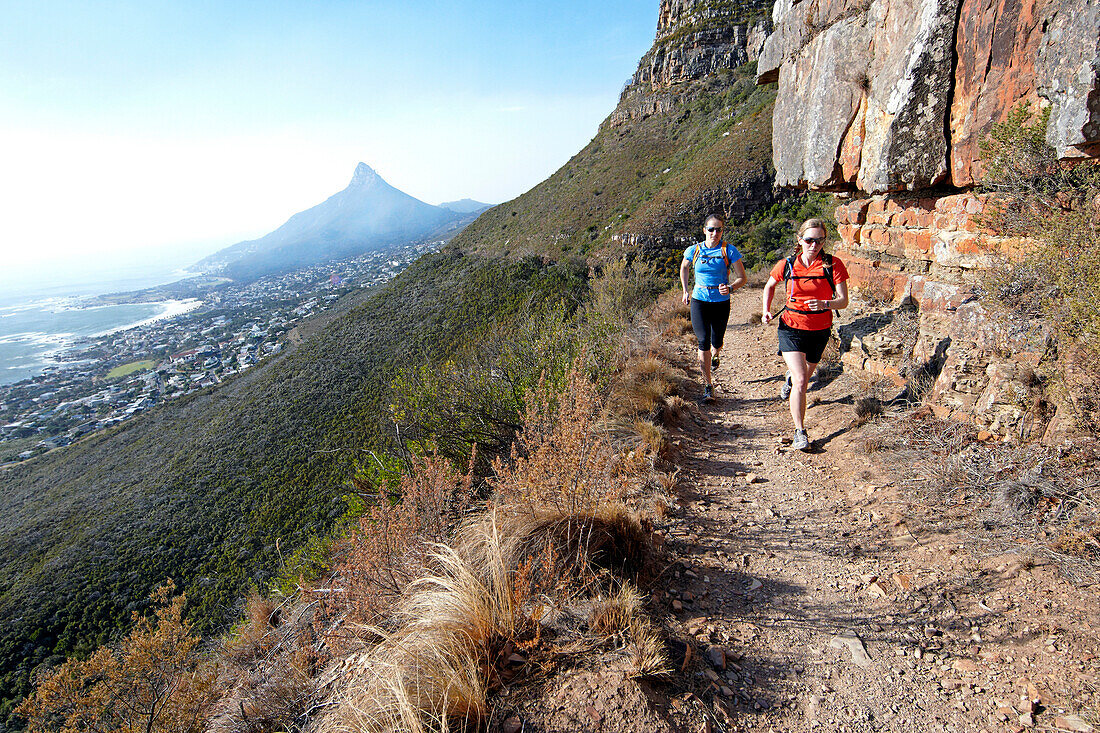 Katrin Schneider and Susann Scheller running on the Pipe Track above Camps Bay and below the Twelve Apostles. Cape Town, South Africa.