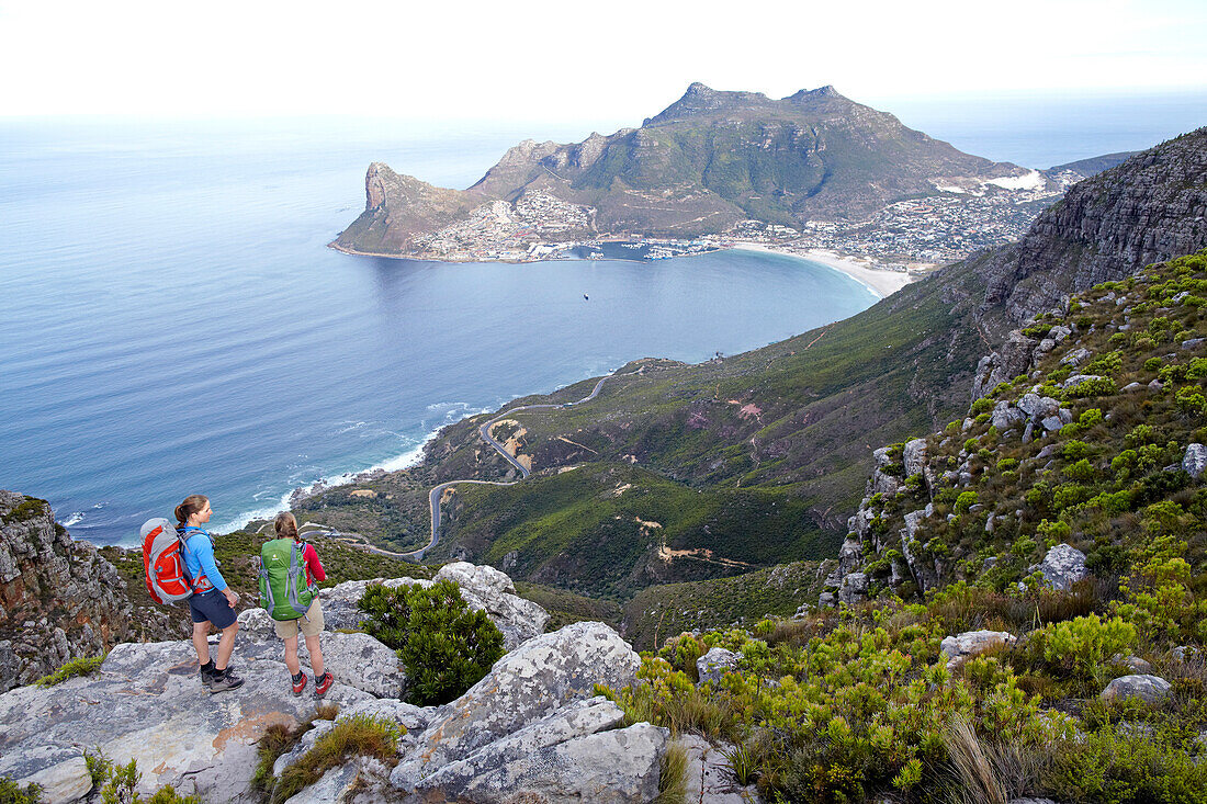Katrin Schneider and Susann Scheller having a break with a vew of Hout Bay, while hiking on the Hoerikwaggo Trail from Cape Point to Table Mountain in Cape Town. South Africa.