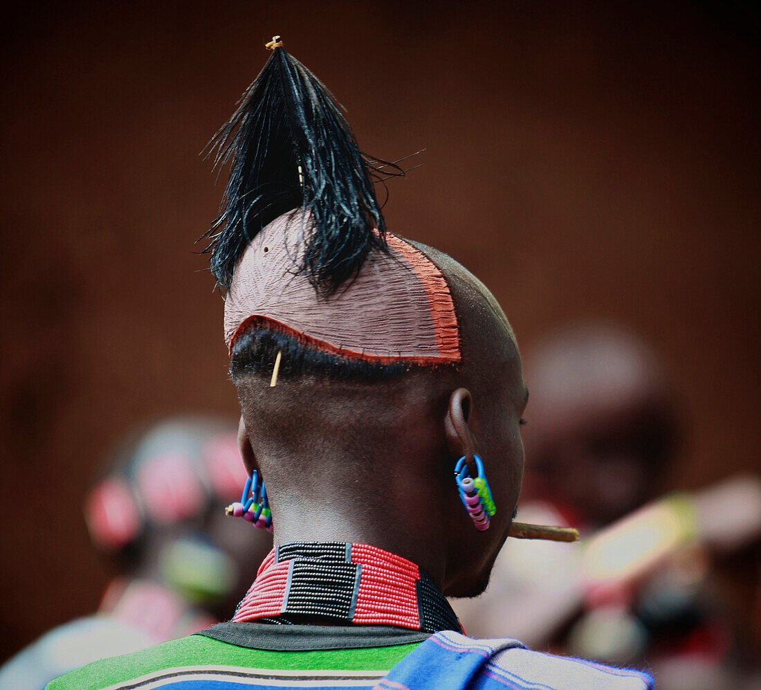 Hamar men wear clay hair buns representing killing of an enemy or a dangerous animal. The hairdo lasts up to one year. Above the forehead, a small holder is made to hold ostrich feathers. To protect their hairdos, Hamar men at all times carry with them a 