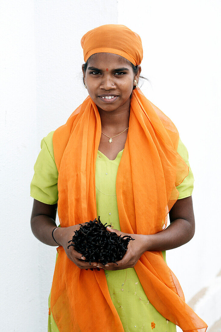 Indian woman holding vanilla beans.