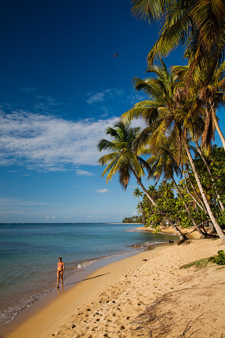 A woman enjoys a leisurely walk on a secluded beach in Las Terrenas.