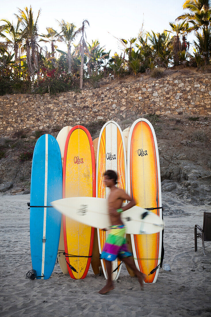 A surfer runs to the waves next to a stack of boards at Los Cerritos near Pescadero, Mexico.