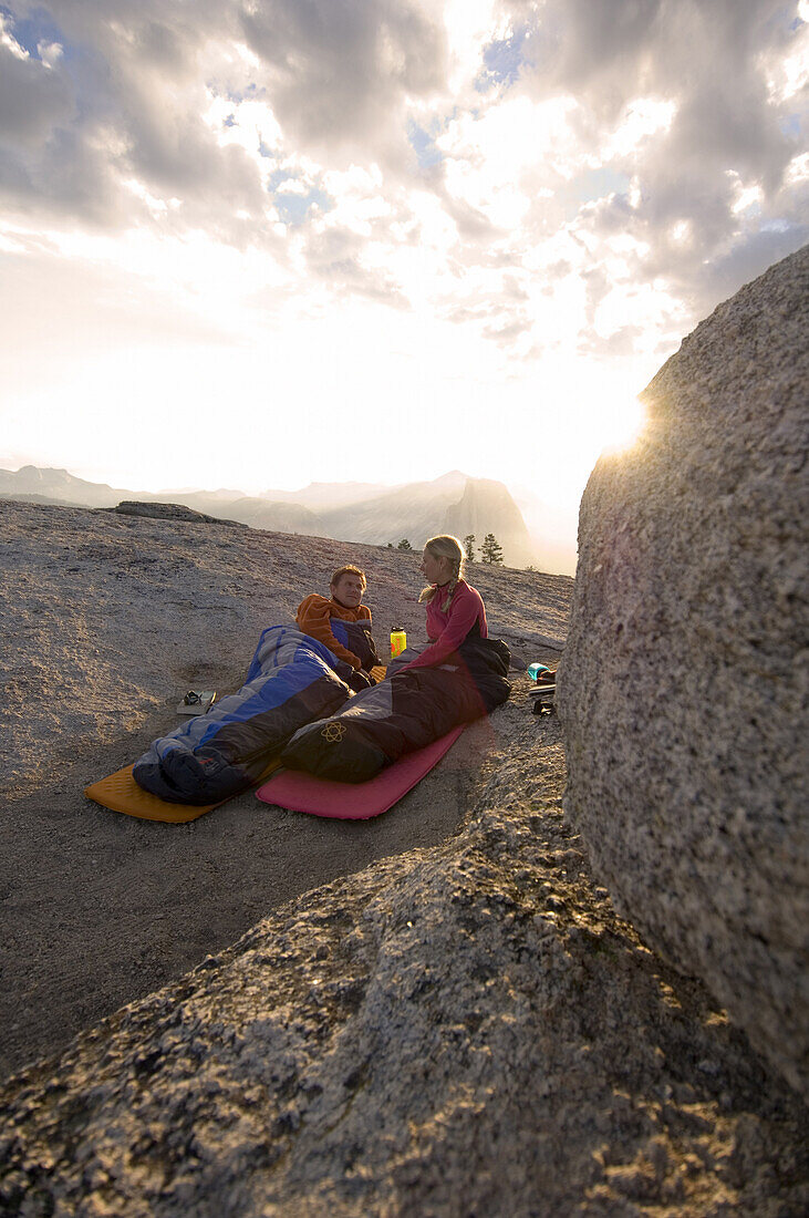 Just after sunrise. Katrin Griebeling and Jens Martin lying in their sleeping bags on top of Sentinel Dome in Yosemite National Park, California, USA.