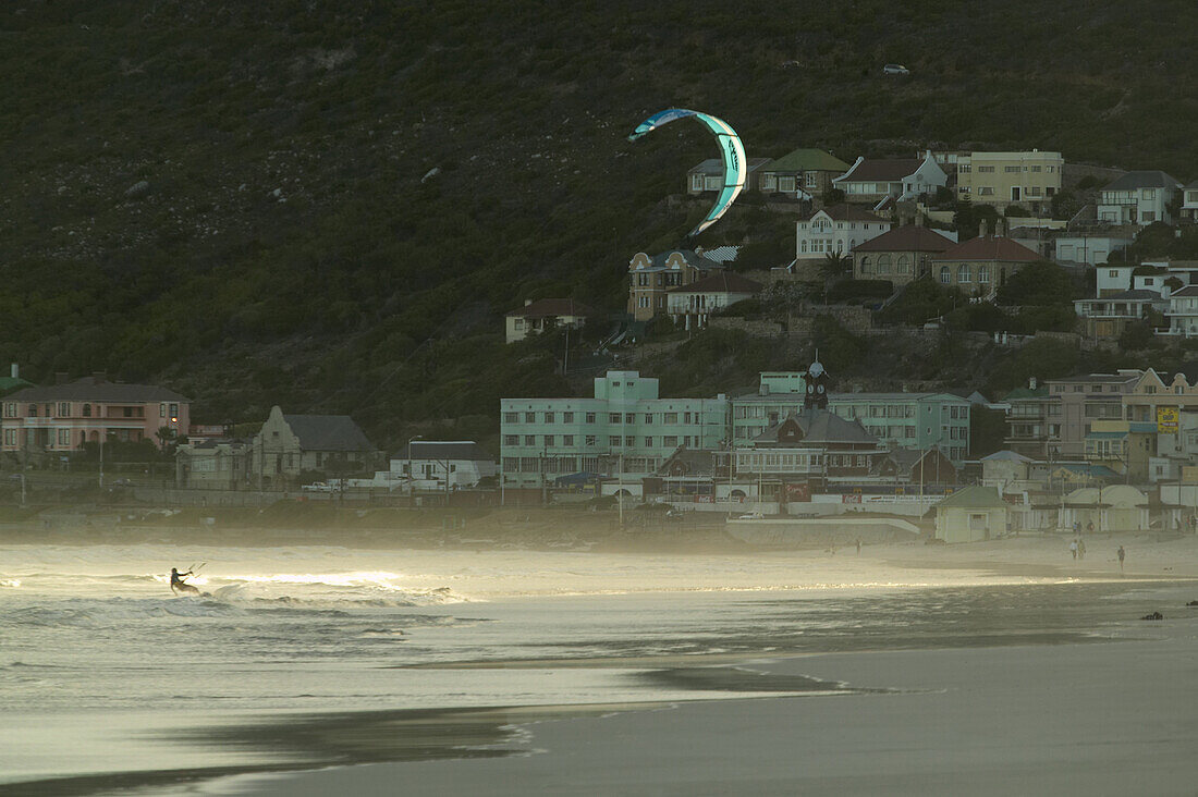 Kiteboarder Christian Schlebach rides through haze and late afternoon light in Muizenberg, Capetown, South Africa