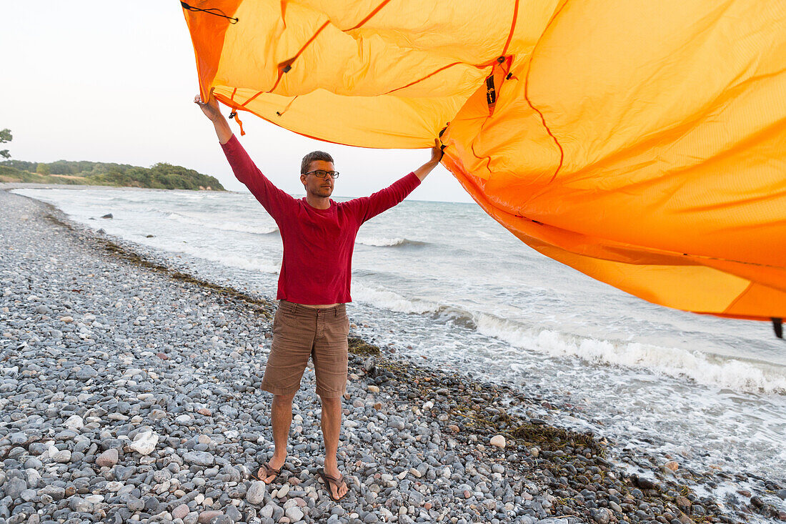 Man holding tent in the wind, Klintholm, Mon island, Denmark