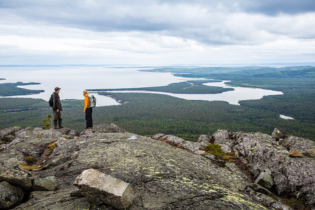 Two hikers on summit of mountain Kivakkatunturi, Paanajaervi National Park, Republic of Karelia, Russia