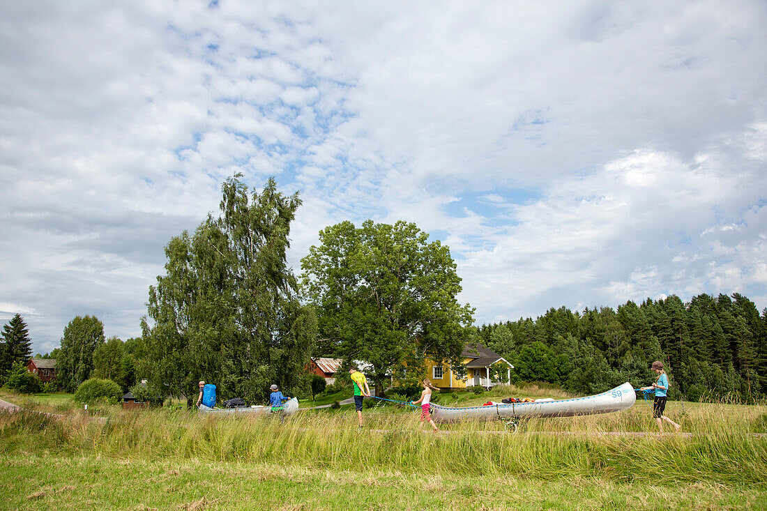 Family transporting canoes and luggage along a road from lake Glafsfjorden to lake Vaermeln, Vaermland, Sweden