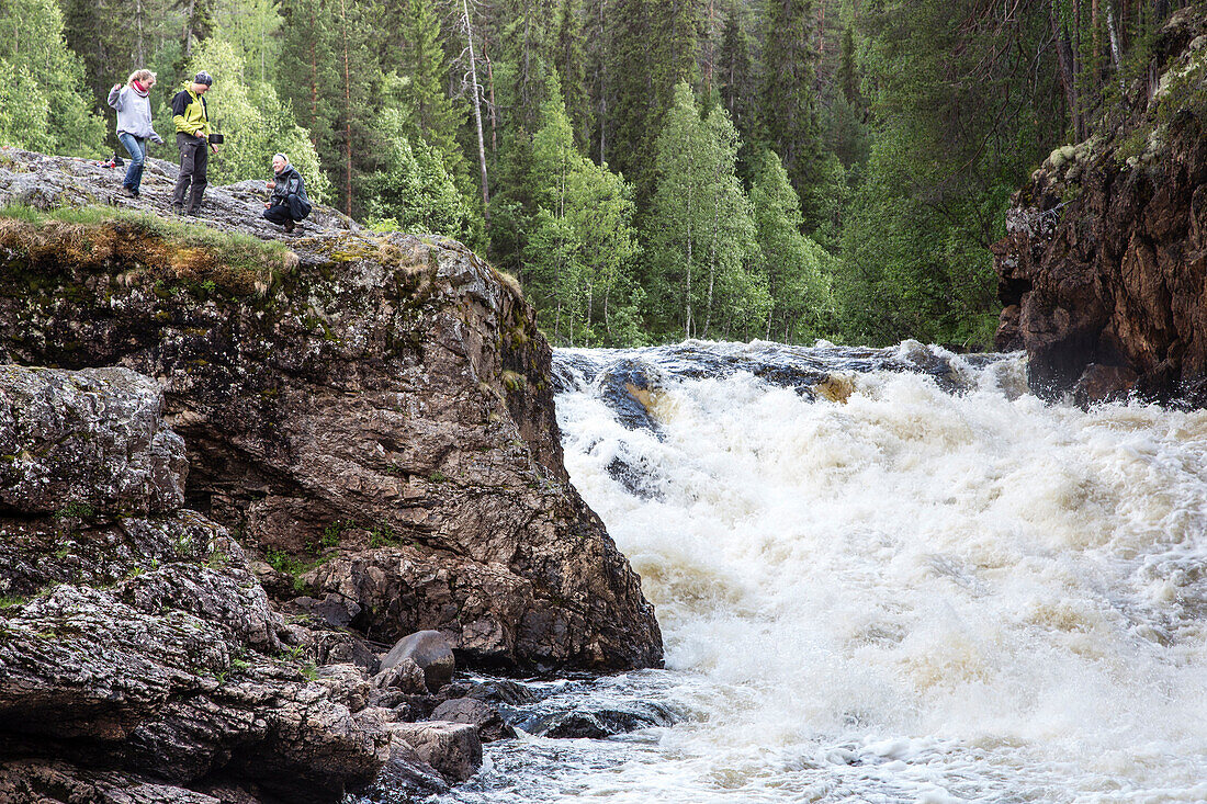 Drei Wanderer am Wasserfall Kiutaköngäs, Nationalpark Oulanka, Nordösterbotten, Finnland