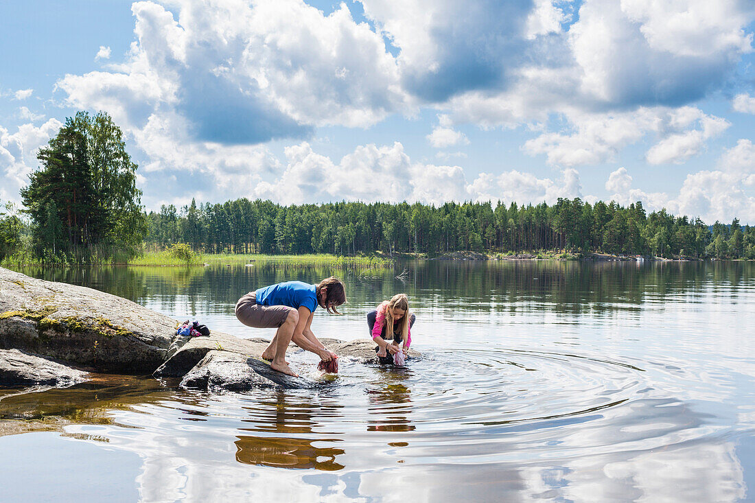 Mutter und Tochter waschen Kleider am Värmelnsee, Värmland, Schweden