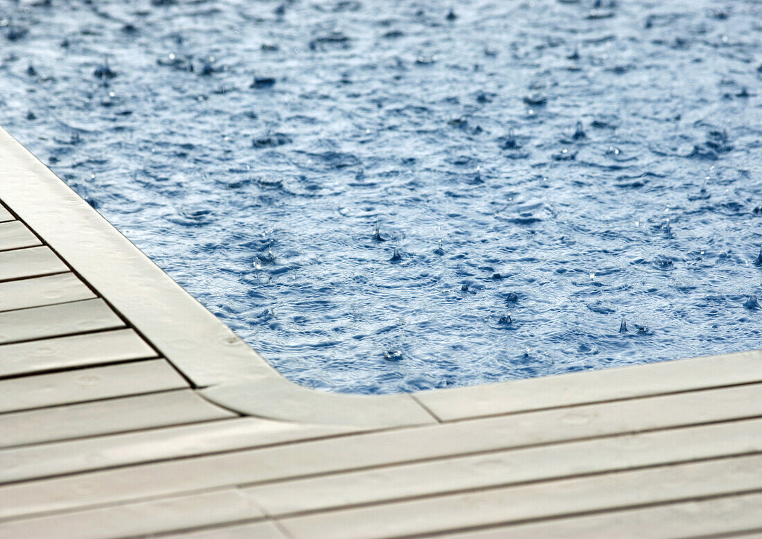 Rain falling on surface of swimming pool