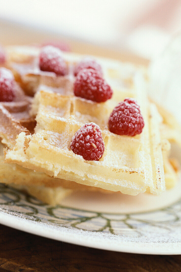 Waffles topped with raspberries and powdered sugar
