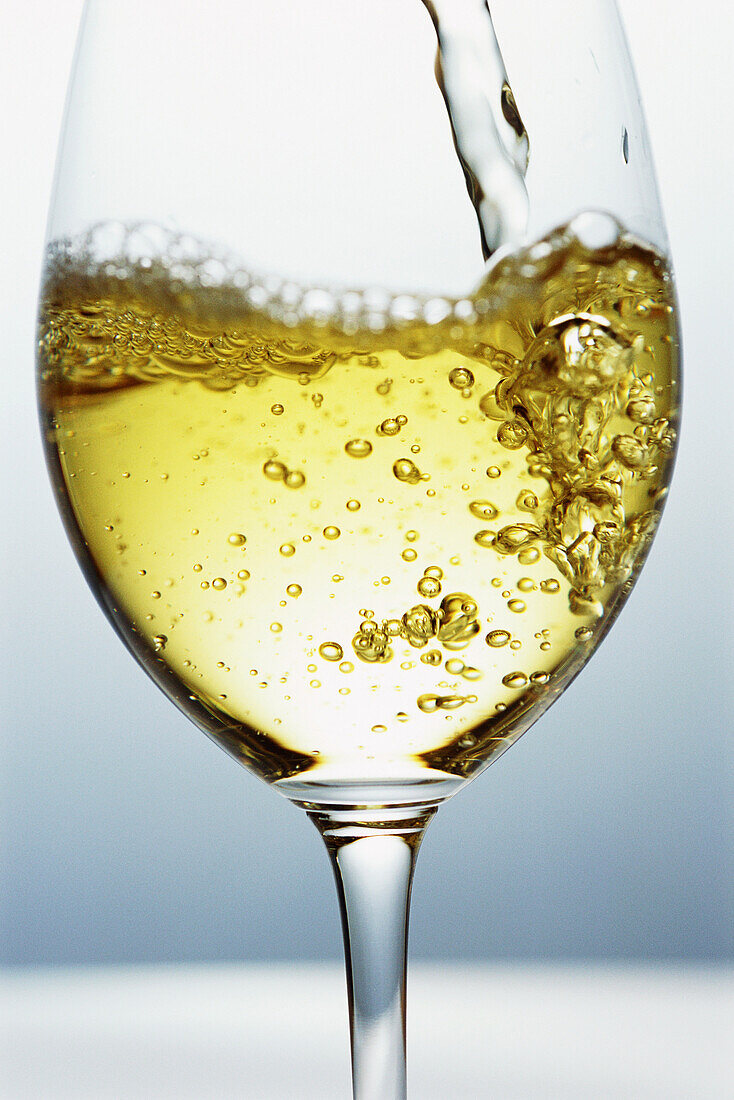White wine being poured into wine glass, close-up