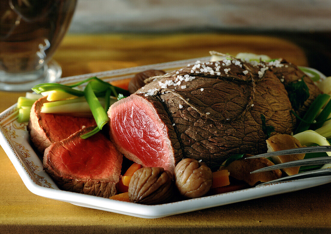 Roast beef with vegetables on dish, close-up