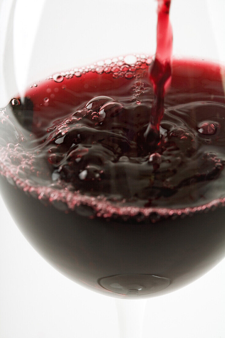 Red wine pouring into glass, close-up