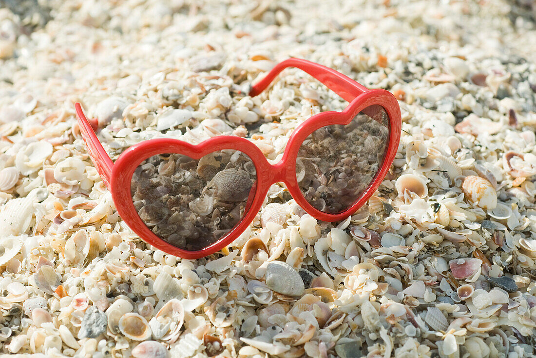Heart-shaped sunglasses on beach