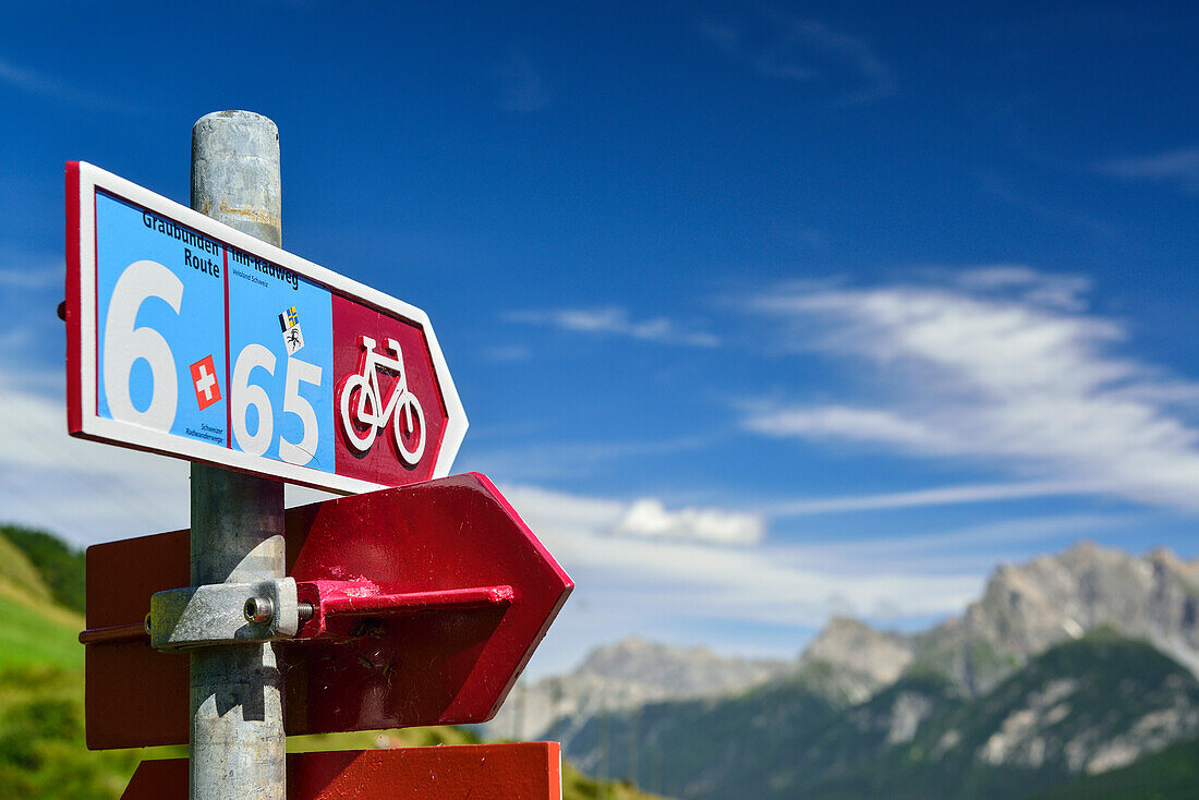 Cycle route signpost with mountains in background, Lower Engadin, Canton of Graubuenden, Switzerland