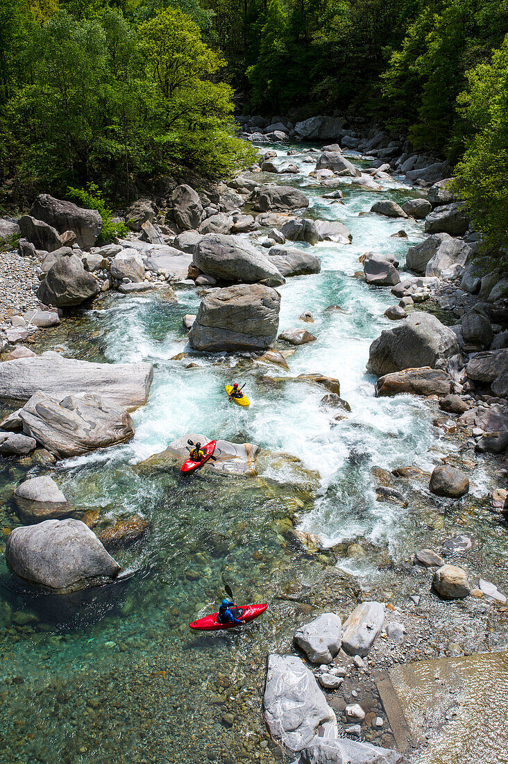 Three kayaker in a rapid on the crystal clear waters of the Verzasca, Ticino, Switzerland