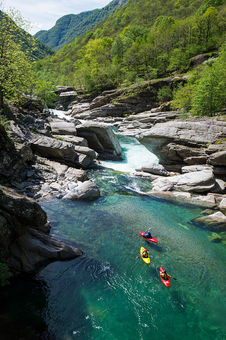 Three kayakers on the crystal clear waters of the Verzasca, Ticino, Switzerland