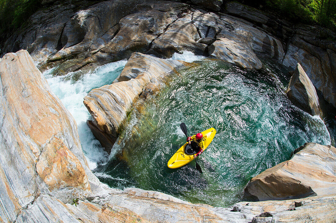 Kayaker in bedrock on the crystal clear waters of the Verzasca, Ticino, Switzerland