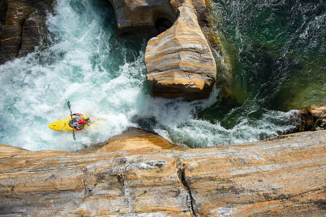 Kayaker in bedrock in the crystal clear waters of the Verzasca, Ticino, Switzerland